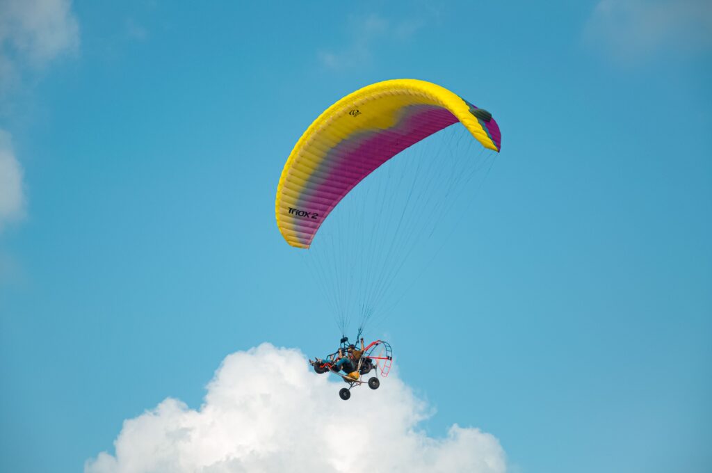 Colorful paraglider enjoying a sunny day adventure against a cloud-studded sky.